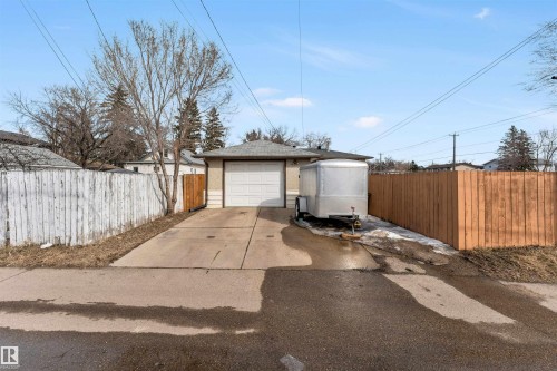The property features a garage with a white door, a paved driveway, and perimeter fencing - 12908 126 Street, Edmonton, AB - Outdoor