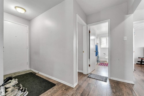 The property features wood-look flooring throughout the hallway, leading to a bathroom with a window and a toilet - 12908 126 Street, Edmonton, AB - Indoor Photo Showing Other Room