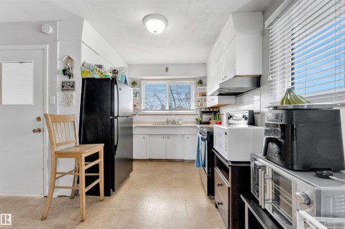 The kitchen features white cabinetry, a large window providing natural light, and ample counter space - 12908 126 Street, Edmonton, AB - Indoor Photo Showing Kitchen