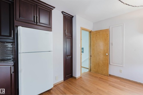 The kitchen features dark wood cabinetry, a white refrigerator, and a tiled backsplash - 11815 76 Avenue, Edmonton, AB - Indoor