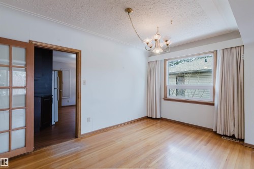 Room featuring hardwood floors, a window with exterior views, and a chandelier - 11815 76 Avenue, Edmonton, AB - Indoor Photo Showing Other Room
