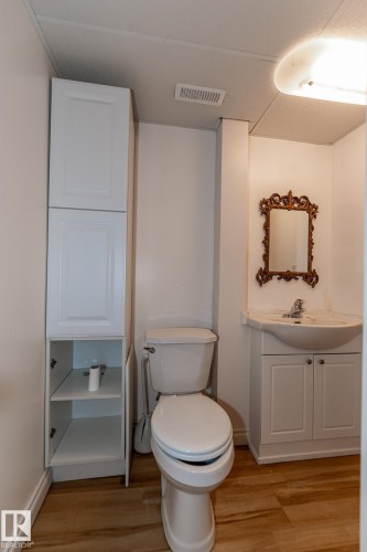 Bathroom featuring a white toilet, a vanity with a sink, and a tall storage cabinet - 11815 76 Avenue, Edmonton, AB - Indoor Photo Showing Bathroom