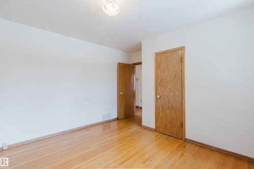 This room features hardwood floors and white walls, complemented by natural wood doors and trim - 11815 76 Avenue, Edmonton, AB - Indoor Photo Showing Other Room
