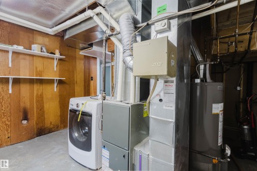 The utility area features a water heater, furnace, and washer, with two wall-mounted shelves for storage - 11815 76 Avenue, Edmonton, AB - Indoor Photo Showing Laundry Room