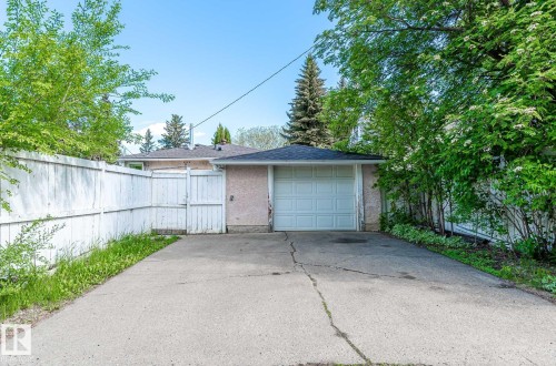 The property features a private driveway leading to an attached garage with a white sectional door - 11815 76 Avenue, Edmonton, AB - Outdoor