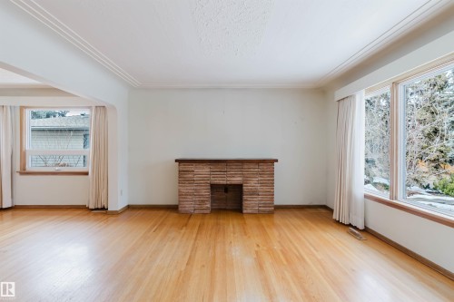 The property features hardwood floors, a brick fireplace, and large windows that provide natural light - 11815 76 Avenue, Edmonton, AB - Indoor With Fireplace