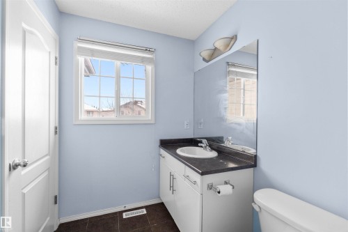 Bathroom featuring a vanity with a white sink, dark countertop, and a window providing natural light - 11542 18A Avenue, Edmonton, AB - Indoor Photo Showing Bathroom