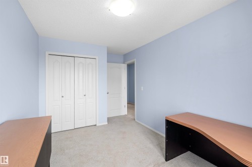 The property features a room with light blue walls, gray carpet, and a white bi-fold closet - 11542 18A Avenue, Edmonton, AB - Indoor Photo Showing Other Room