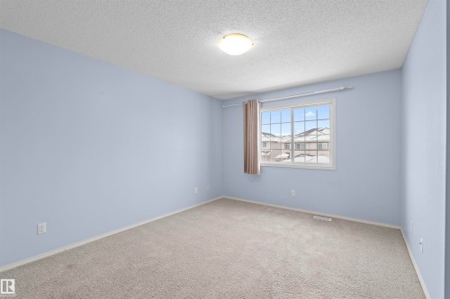 This room features light blue walls, neutral-toned carpeting, and a window with a grid pattern - 11542 18A Avenue, Edmonton, AB - Indoor Photo Showing Other Room