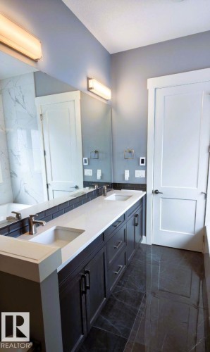 Bathroom featuring a double vanity with white countertops, dark cabinetry, and dual undermount sinks - 1781 Melrose Crescent, Edmonton, AB - Indoor Photo Showing Bathroom