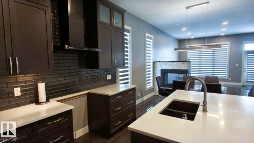 Modern kitchen featuring dark cabinetry, light countertops, and a double basin sink with a curved faucet - 1781 Melrose Crescent, Edmonton, AB - Indoor Photo Showing Kitchen With Double Sink