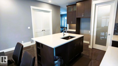 The kitchen features an island with a white countertop and an undermount sink with a gooseneck faucet - 1781 Melrose Crescent, Edmonton, AB - Indoor