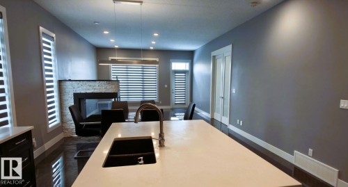 The kitchen features a large island with a sink and a stainless steel faucet - 1781 Melrose Crescent, Edmonton, AB - Indoor With Fireplace