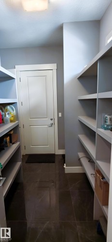 Storage area featuring extensive built-in shelving, a white door with trim, and dark tile flooring - 1781 Melrose Crescent, Edmonton, AB - Indoor