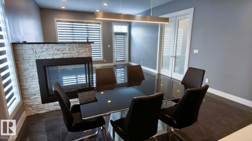 Dining area featuring a stone fireplace, recessed lighting, and a modern linear chandelier - 1781 Melrose Crescent, Edmonton, AB - Indoor With Fireplace