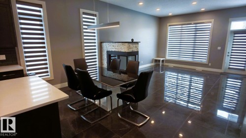 The property features dark tile flooring, a stone-faced fireplace, and recessed ceiling lights - 1781 Melrose Crescent, Edmonton, AB - Indoor With Fireplace