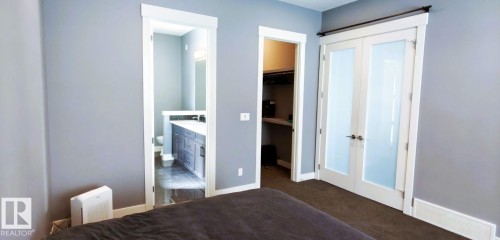 The property features a bathroom with a vanity and toilet, a walk-in closet, and double doors with frosted glass panels - 1781 Melrose Crescent, Edmonton, AB - Indoor