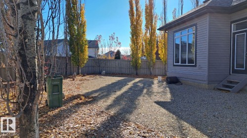 The property features a fenced yard with tall, mature trees and a gravel surface, providing a low-maintenance outdoor space - 1781 Melrose Crescent, Edmonton, AB - Outdoor