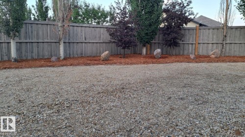 The property features a gravel ground cover, a wooden fence, and mature trees - 1781 Melrose Crescent, Edmonton, AB - Outdoor