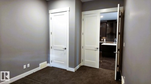 Interior space featuring neutral-toned walls, contrasting white trim, and dark brown carpeting - 1781 Melrose Crescent, Edmonton, AB - Indoor Photo Showing Other Room