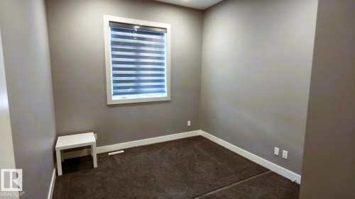 The room features neutral-toned walls, dark carpeting, and a window with blinds - 1781 Melrose Crescent, Edmonton, AB - Indoor Photo Showing Other Room