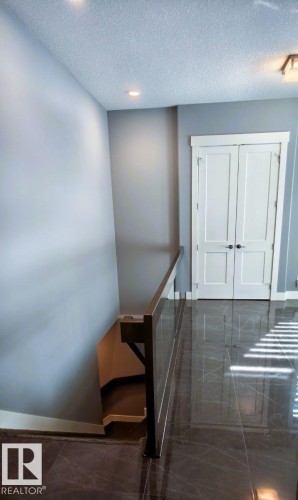 The property features a hallway with dark, polished tile flooring, light grey walls, and white double doors - 1781 Melrose Crescent, Edmonton, AB - Indoor Photo Showing Other Room