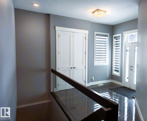 The entrance features a glass-paneled front door, two windows with horizontal blinds, and a built-in closet with double doors - 1781 Melrose Crescent, Edmonton, AB - Indoor Photo Showing Other Room