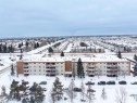 The property features a multi-story building with balconies, surrounded by a landscaped area with trees and parking - 401 3611 145 Avenue, Edmonton, AB  - Outdoor With View 