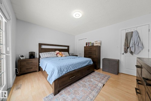 Bedroom featuring light-colored flooring, a white door with a window, and a light fixture on the ceiling - 5418 17A Avenue, Edmonton, AB - Indoor Photo Showing Bedroom