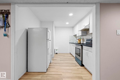 Kitchen featuring white cabinetry, a stainless steel oven, dark countertops, and light wood-style flooring - 5418 17A Avenue, Edmonton, AB - Indoor Photo Showing Kitchen