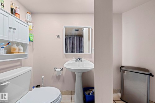 This bathroom features a pedestal sink with a mirror, a toilet, and tiled flooring - 5418 17A Avenue, Edmonton, AB - Indoor Photo Showing Bathroom
