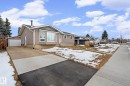 The property features a grey exterior, a front yard with a partial lawn, and a paved driveway leading to a garage - 5418 17A Avenue, Edmonton, AB  - Outdoor 