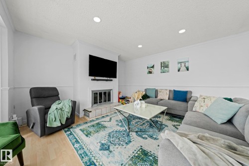Living area featuring a fireplace with a tiled hearth, light-toned flooring, and recessed lighting - 5418 17A Avenue, Edmonton, AB - Indoor Photo Showing Living Room With Fireplace