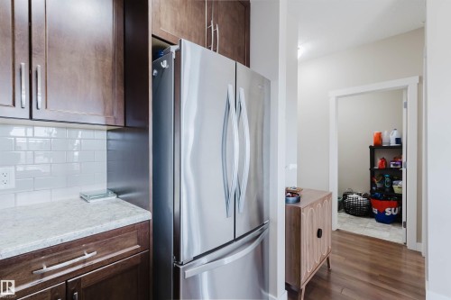 The kitchen features wood cabinetry, a light-colored countertop, and a white subway tile backsplash - 402 3670 139 Avenue, Edmonton, AB - Indoor Photo Showing Kitchen With Stainless Steel Kitchen