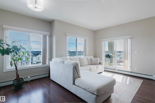 Living area featuring dark hardwood floors, light-colored walls, and a recessed ceiling light fixture - 402 3670 139 Avenue, Edmonton, AB - Indoor Photo Showing Living Room