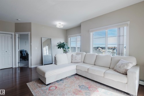 Living area featuring dark wood flooring, light-colored walls, and windows with white blinds - 402 3670 139 Avenue, Edmonton, AB - Indoor Photo Showing Living Room
