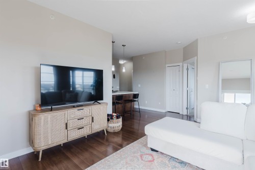 Living area featuring hardwood flooring, light-colored walls, and a view of the kitchen area with pendant lighting - 402 3670 139 Avenue, Edmonton, AB - Indoor Photo Showing Living Room