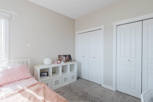 This room features carpeted flooring, light-colored walls, and two sets of white bi-fold closet doors - 402 3670 139 Avenue, Edmonton, AB - Indoor Photo Showing Bedroom