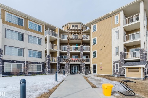 The property features a multi-story building with a light-colored exterior and stone accents - 402 3670 139 Avenue, Edmonton, AB - Outdoor With Balcony With Facade