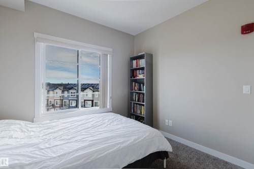 This room features light gray walls, a window with a view of residential properties, and gray carpeting - 402 3670 139 Avenue, Edmonton, AB - Indoor Photo Showing Bedroom
