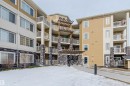 The property features a multi-story building with a light-colored facade, contrasting with dark stone accents on the lower levels and support pillars - 402 3670 139 Avenue, Edmonton, AB  - Outdoor With Balcony With Facade 