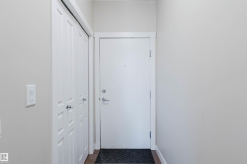 Entryway featuring a white paneled closet, light-colored walls, and a wood floor - 402 3670 139 Avenue, Edmonton, AB - Indoor Photo Showing Other Room