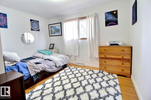 This room features hardwood floors and a window with white curtains, providing natural light - 243 Lynnwood Way, Edmonton, AB - Indoor Photo Showing Bedroom