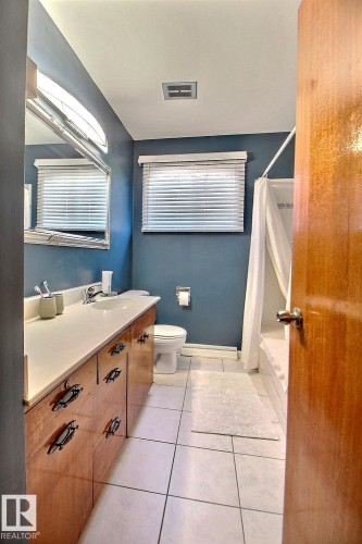 Bathroom featuring a wood vanity with a white countertop, a mirror, and a window with blinds - 243 Lynnwood Way, Edmonton, AB - Indoor Photo Showing Bathroom