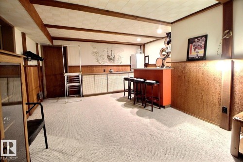 Recreation room featuring exposed wood beams, wood wall paneling, and a wet bar with stools - 243 Lynnwood Way, Edmonton, AB - Indoor Photo Showing Other Room