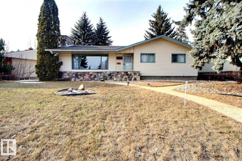 The property features a front yard with a concrete walkway leading to the entry, a stone skirt facade, and a light-colored exterior with a contrasting roof trim - 243 Lynnwood Way, Edmonton, AB - Outdoor With Deck Patio Veranda