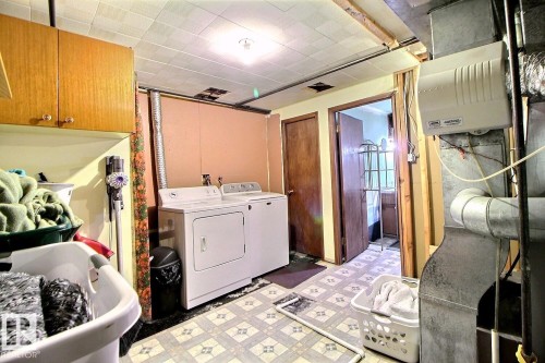 Utility space featuring a washer and dryer, wood cabinetry, and patterned floor tiles - 243 Lynnwood Way, Edmonton, AB - Indoor Photo Showing Laundry Room
