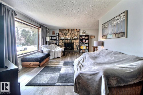 The living room features a stone fireplace, hardwood flooring, and a large picture window - 243 Lynnwood Way, Edmonton, AB - Indoor Photo Showing Bedroom