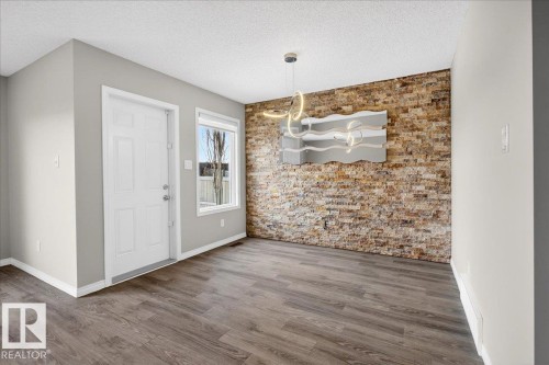 The property features hardwood style flooring, a stone accent wall, and a modern light fixture - 17023 38 Street Nw, Edmonton, AB 
