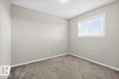 This room features neutral-toned walls, a window with horizontal blinds, and carpeting - 17023 38 Street Nw, Edmonton, AB 